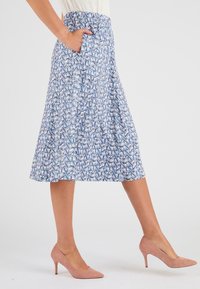 Jupe bleue à motifs avec une taille élastique ajustée et des poches, présentant un design géométrique dans des tons blancs et roses.