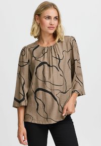 Braune Bluse mit schwarzen abstrakten Linienmustern. Besitzt einen runden Ausschnitt und Dreiviertelärmel, hat eine strukturierte Textur und eine lockere Passform.