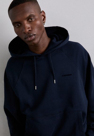 Felpa blu navy in tessuto morbido, dotata di tasca a marsupio, cordini regolabili e un logo discreto sul petto.