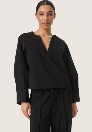 Pulover negru cu decolteu adânc în V, mâneci lungi și o croială lejeră. Are o textură în dungi și un design simplu. Se combină cu pantaloni asortati.