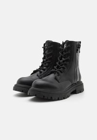 Black leather ankle boots with textured surface, round toe, lace-up front, and side zipper; features a rugged, chunky sole.