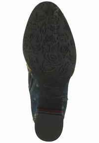 Suola di scarpa in gomma nera con incisioni floreali. I lati presentano un tessuto in denim con accenti di cuciture colorate. Design piatto, punta leggermente arrotondata.