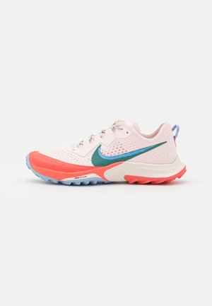 Jasnoróżowy i koralowy but do biegania z turkusowo-niebieskim logo Nike, białą podeszwą oraz niebiesko-koralowym bieżnikiem na białym tle.