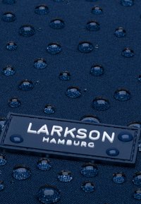 Marinblått tyg med texturerad yta, prydd med vattendroppar och en svart etikett med vita bokstäver märkta "LARKSON HAMBURG."