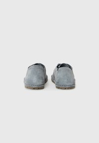 Gray suede slip-on shoes feature a low profile, rounded edges, and a textured sole. The design includes minimal stitching and no visible hardware.