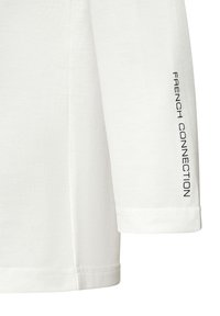 Weißes Langarmshirt aus weichem Baumwollstoff, mit einem schwarz bedruckten Logo auf dem linken Ärmel und einem schlichten Rundhalsausschnitt.