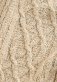 Beige Strickpulloverstoff mit strukturierten Zopfmustern und einer weichen, flauschigen Oberfläche. Das Design enthält Diamantformen und erhöhte Drehungen.