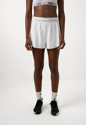 Pantaloni corti sportivi bianchi con vita elastica, texture liscia e vestibilità ampia, abbinati a sneakers nere e calzini bianchi Nike.