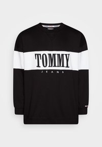 Sudadera negra con rayas horizontales blancas. Presenta "TOMMY JEANS" en letras negras de forma prominente. Material de algodón, cuello redondo, mangas largas.