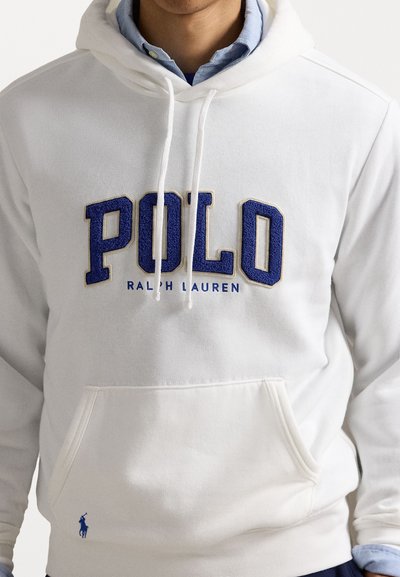 Bela kapuca z modrim napisom "POLO" in majhnim modrim logotipom konja. Ima žep v obliki kenguruja in kapuco z vrvico. Mehka tkanina.