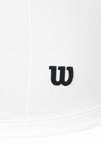 Camiseta deportiva blanca con un acabado texturizado; cuenta con un prominente logo negro de "W" en la parte inferior izquierda.