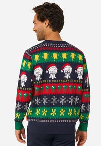 Kootud kampsun, millel on tumesinine taust ja värvikad mustrid, sealhulgas lumememmed, pidulikud tegelased ja pühasümbolid, resiinist varrukate äärtega.