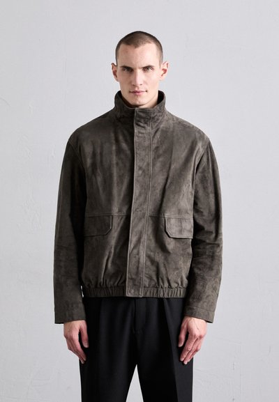 Suede bomber jakna u tamnosivoj boji s visokim ovratnikom, dva prednja džepa, elastičnom donjom ivicom i minimalističkim dizajnom. Glatka tekstura.