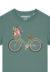T-shirt vert avec un motif de bicyclette, dotée d'un siège marron, de roues noires et d'un panier en osier rempli de fleurs roses.
