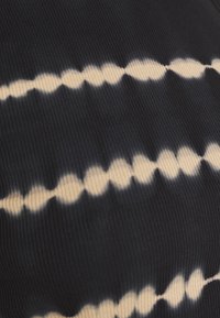 Tissu côtelé bleu marine foncé avec un motif tie-dye de points et lignes couleur crème, créant une texture visuelle contrastée.