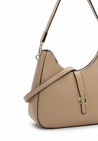 Bolso de hombro de cuero beige con un diseño estructurado, ribete negro y un acento de hardware circular dorado en el frente. Incluye una correa ajustable.