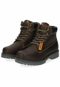 Botas de tobillo de cuero marrón con suelas de goma gris, cuentan con ojales de metal, cordones beige y una etiqueta con detalles en naranja. Textura suave en general.