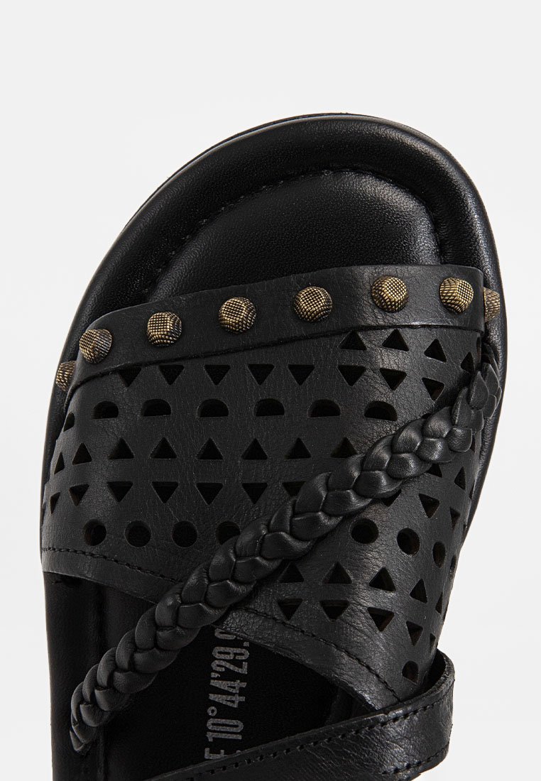 Schwarze Leder-Sandale mit ausgeschnittenen geometrischen Mustern, geflochtenen Riemen und strukturierten metallic Nieten im Obermaterial.