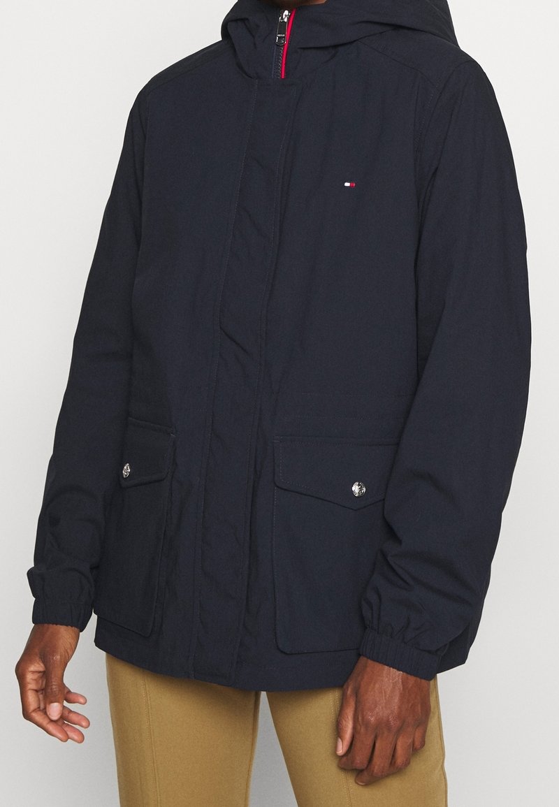 Námořnická hooded bunda vyrobená z odolné látky. Má centrální zip, dvě přední kapsy se zařezávacími uzávěry a elastické manžety.