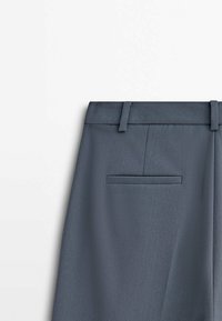 Grijze broek met een gladde textuur, voorzien van een tailleband met riemlussen en een enkele achterzak. Eenvoudig ontwerp, geen patronen of accenten.