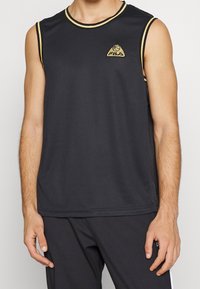 Schwarzes ärmelloses Basketballtrikot aus Netzstoff, mit Rundhalsausschnitt und goldenen Akzenten, ausgestattet mit einem dreieckigen Logo auf der Brust.
