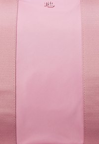 Rosa tygväska med mjuk textur, som har en central stor panel och sydda kanter. Logotypen "RL" präglad i det övre området.