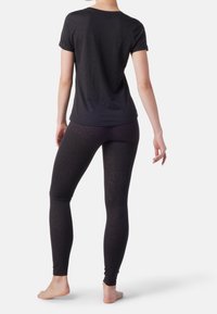 Top nero a maniche corte e leggings neri attillati con un motivo discreto. Il tessuto appare liscio ed elastico, con una consistenza morbida.