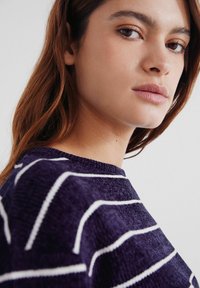 Námořnický modrý svetr s bílými pruhy, s kulatým výstřihem a texturovanou látkou, zobrazený z úhlu tří čtvrtin.