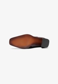 Brown leather shoe sole with a smooth, slightly textured finish. Features a rounded toe and a low, square black heel.