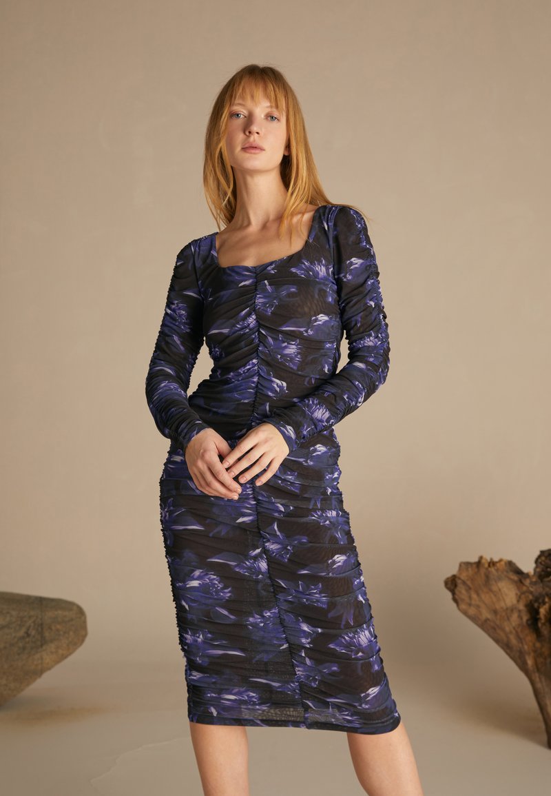Black bodycon dress with long sleeves, featuring a floral pattern in blue and purple. Textured fabric with gathered detailing throughout.