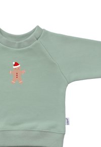Mint green sweatshirt with ribbed cuffs and neckline. Features a gingerbread man graphic with a red hat and candy cane on the front.