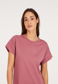 Kurzarm-T-Shirt mit Rundhalsausschnitt in staubrosa, aus weichem Stoff mit lockerer Passform und hochgerollten Ärmeln.