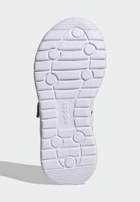 Biela gumená podrážka topánky s textúrovaným gripovým vzorom. Obsahuje kruhové a oválne výstupky pre trakciu, s viditeľným brandingom "adidas".