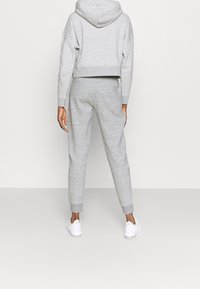 Szara krótka bluza z kapturem i pasujące dresy, wykonane z materiału bawełnianego z prążkowanymi mankietami, luźny krój, z kapturem i detalem kieszeni z tyłu.