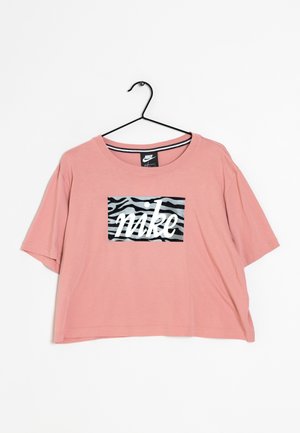 Różowa, krótką rękawem, krótka koszulka z czarnym i szarym wzorem zebry oraz białym tekstem "nike", wisząca na czarnym wieszaku na białym tle.