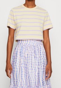 Short-sleeve, cropped T-shirt in pastel yellow with lilac horizontal stripes, paired with a light, pleated checkered skirt in blue and purple hues.