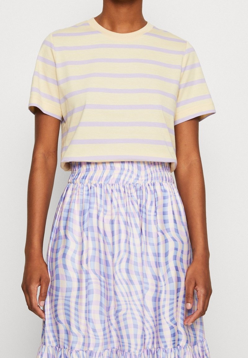 Short-sleeve, cropped T-shirt in pastel yellow with lilac horizontal stripes, paired with a light, pleated checkered skirt in blue and purple hues.