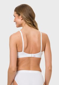 Weißes Bralette mit verstellbaren Trägern, einem Haken- und Ösenverschluss und einer glatten Textur. Mit einem Logodetail am Band.