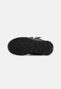 Black rubber sole with deep tread patterns for grip. Reinforced sides and multiple texture elements for durability and support.