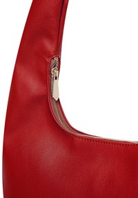 Red leather handbag featuring a smooth texture, curved shape, and a gold-tone zipper accent at the top.