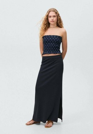 Marine strapless top met witte patronen, gecombineerd met een zwarte maxi rok met een zijsplit. De outfit is gemaakt van een soepele stof.