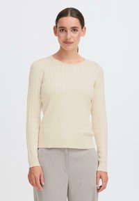 Lichtgekleurde trui met een getextureerd ruitpatroon, lange mouwen en een ronde halslijn, gecombineerd met lichtgrijze broek.