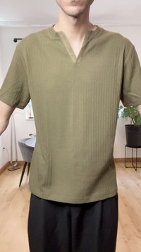 Oliwkowa bluzka z krótkim rękawem o teksturowanym prążkowanym wzorze, z rozciętym dekoltem i luźnym krojem. Prosty design, bez widocznych elementów metalowych ani akcentów.