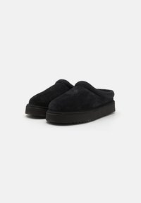Las pantuflas de ante negro presentan una punta redonda, un collar acolchado y una suela de goma gruesa y texturizada para mayor tracción. Diseño ligero y de fácil puesta.