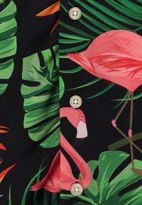 Tessuto nero con foglie tropicali verdi e fenicotteri rosa, con bottoni beige lungo il centro.