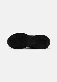 Semelle de chaussure de sport noire avec une surface en caoutchouc texturé et des rainures conçues pour l'adhérence, présentant des cannelures profondes et le nom de la marque "DIESEL."