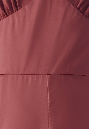 Tissu matelassé rouge avec une texture lisse, présentant des détails froncés en haut et une couture horizontale près du bas.