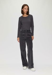 Donkere grijze top met lange mouwen en een ronde halslijn, gecombineerd met brede, donkergrijze corduroy broek en witte sneakers. Eenvoudig, met een gestructureerd ontwerp.
