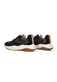 Black leather sneakers with suede accents, a chunky white sole, and beige detailing on the heel. Features laces and contrasting textures.