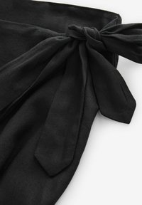 Corbata de tela negra con un acabado texturizado, que presenta un detalle de nudo y dos extremos alargados que cuelgan. Diseño simple y discreto.